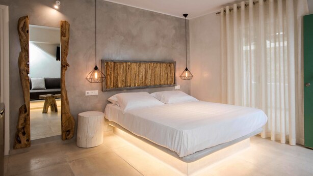 Ein modernes Schlafzimmer mit einem großen Bett, einem Holzkopfstück und Pendelleuchten.