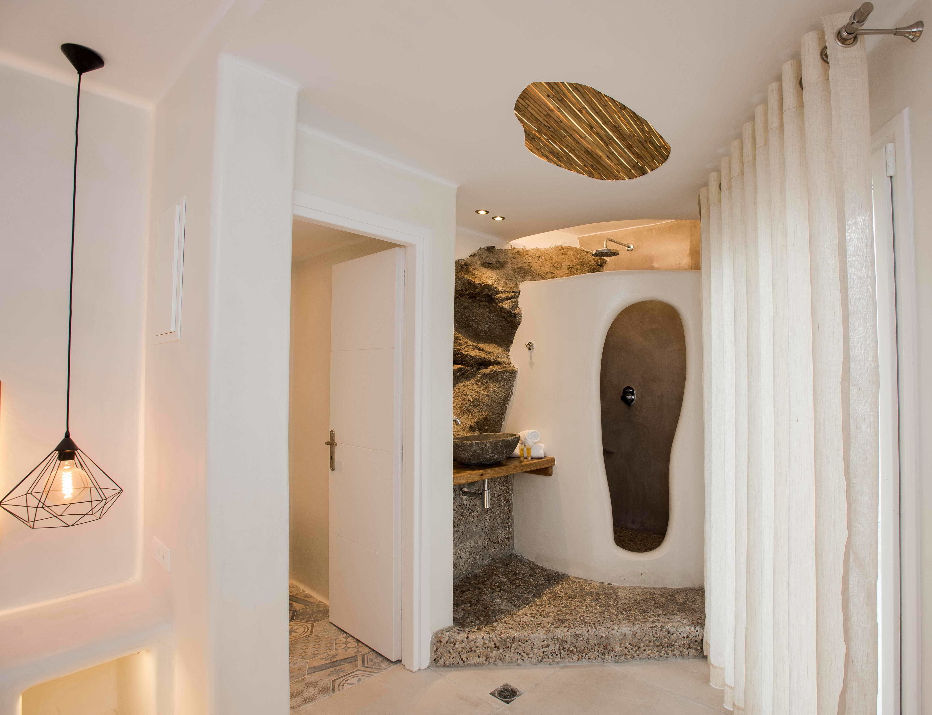 A modern bathroom with a stone wall, a built-in sink, and a unique shower design.