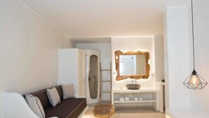 Ein modernes Badezimmer mit einer freistehenden Badewanne, einem Waschtisch inklusive Spiegel und einem hölzernen Hocker.