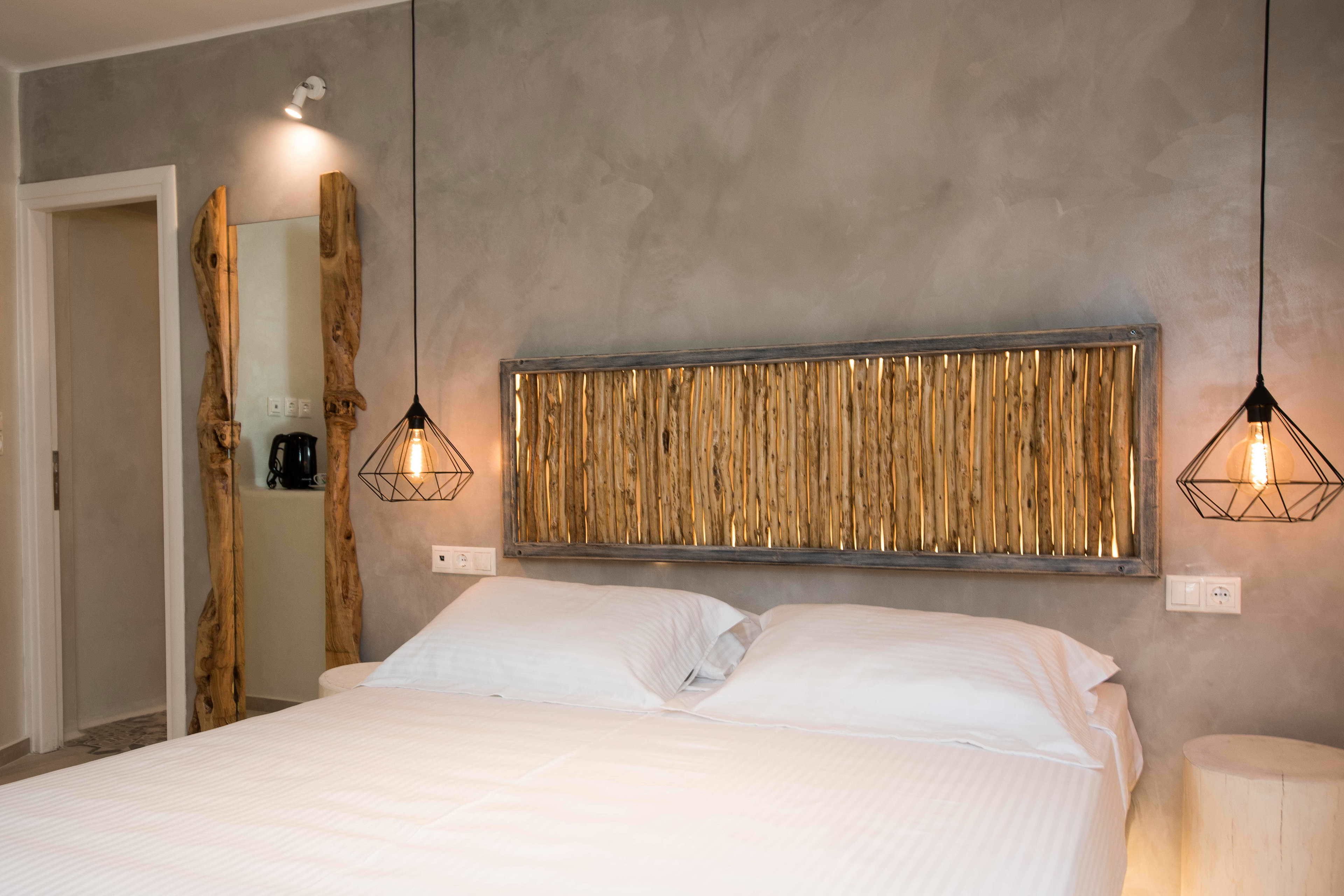 Een slaapkamer met een bed, een houten hoofdbord en hanglampen.