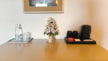 A table with a water bottle, a glass, a tray with a coffee maker, cups, and a tea packet.