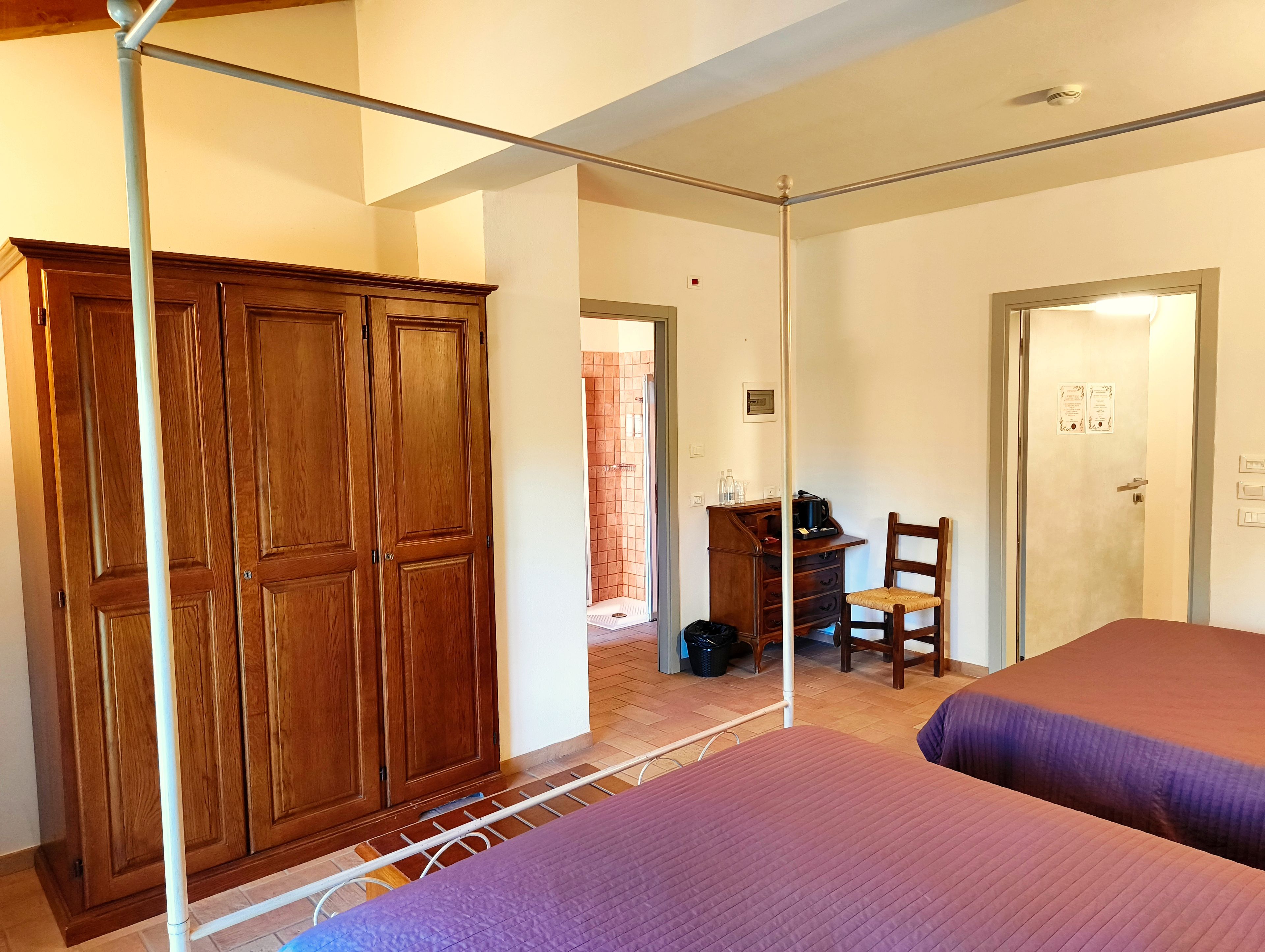 Una habitación con armario, escritorio con silla y dos camas.