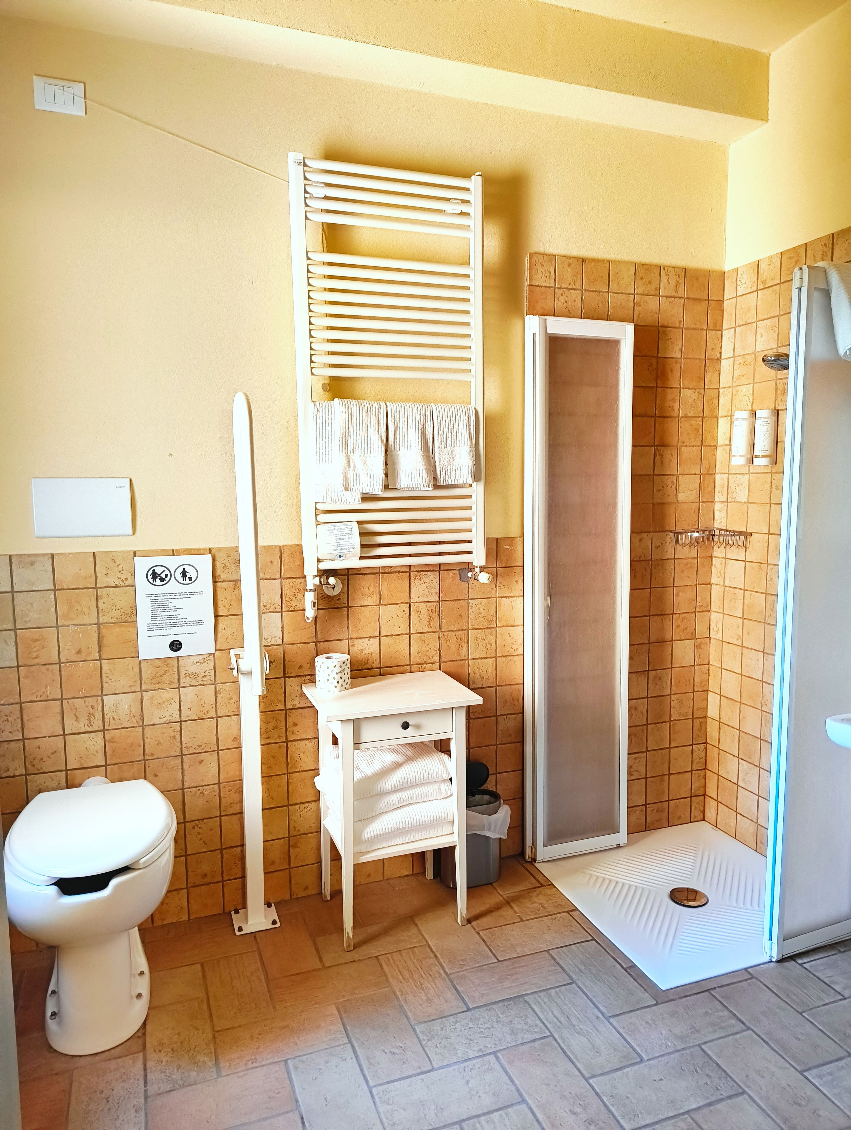 A bathroom with a toilet, a shower, and a towel rack.