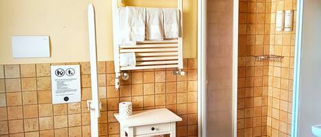 A bathroom with a toilet, a shower, and a towel rack.
