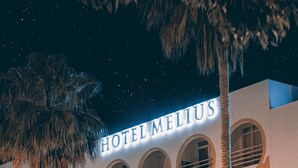 Un hotel con un cartel que dice "HOTEL MELIUS" y varios balcones con barandillas.
