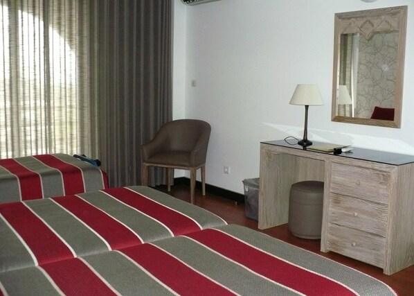 A hotel room with two beds, a desk, a chair, a lamp, and a mirror. - Hotel Melius (Beja)