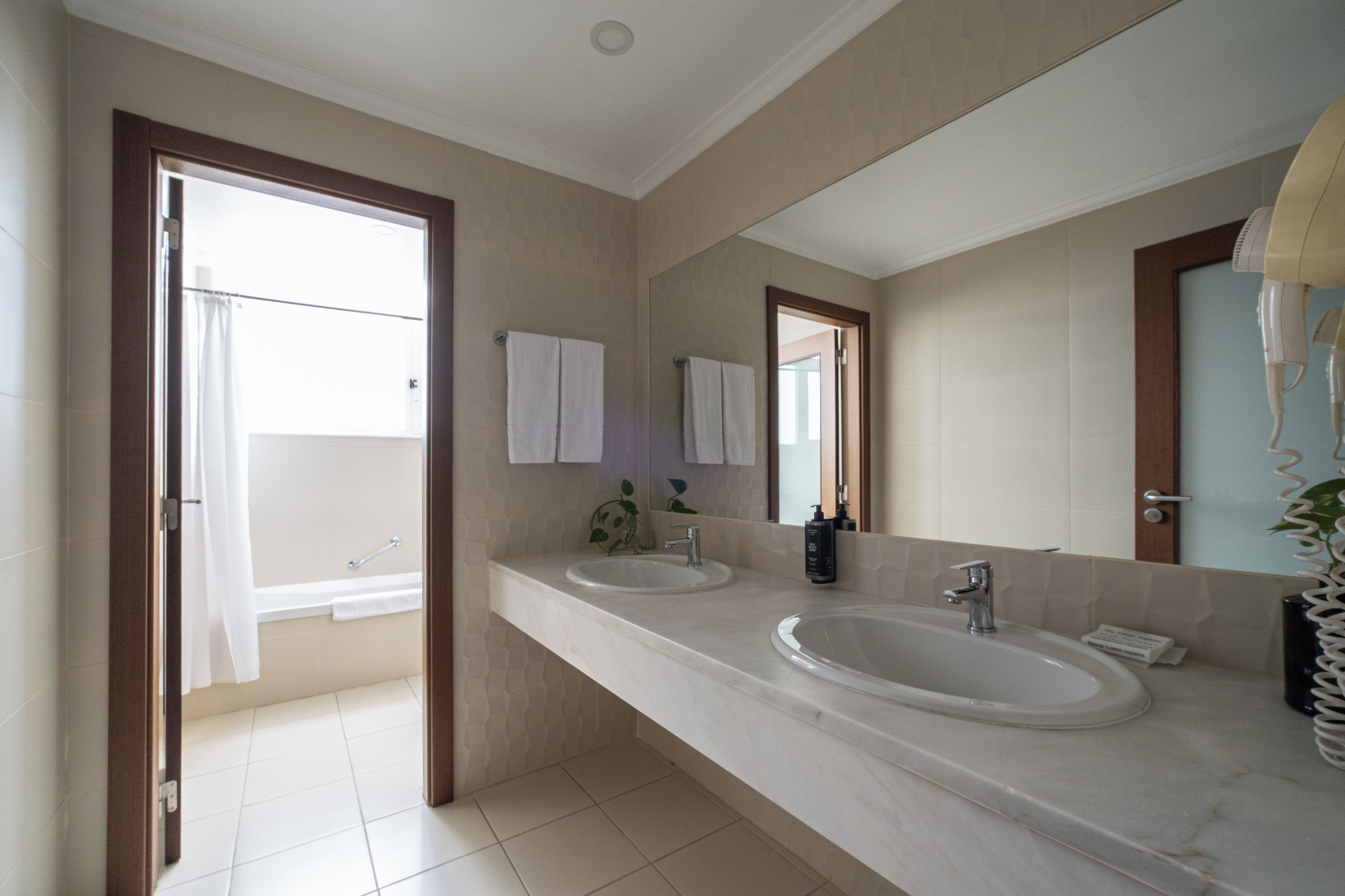 A bathroom with two sinks, a large mirror, and a shower area.