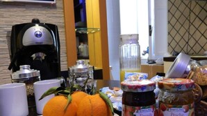 A breakfast table with two oranges, two jars of jam, and a coffee machine. - Romangelo 2 Hostel (Rome)