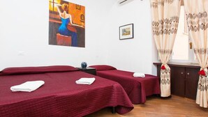 A room with two single beds, a small table, a painting on the wall, and curtains. - Romangelo 2 Hostel (Rome)