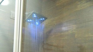 A shower with a glass door and a wooden wall. - Romangelo 2 Hostel (Rome)