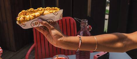 Una mesa con mantel a cuadros, una tabla de madera con galletas, un vaso de bebida roja y una botella de agua.