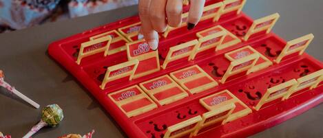 A hand placing a card on a game board with multiple cards and a lollipop on the table.