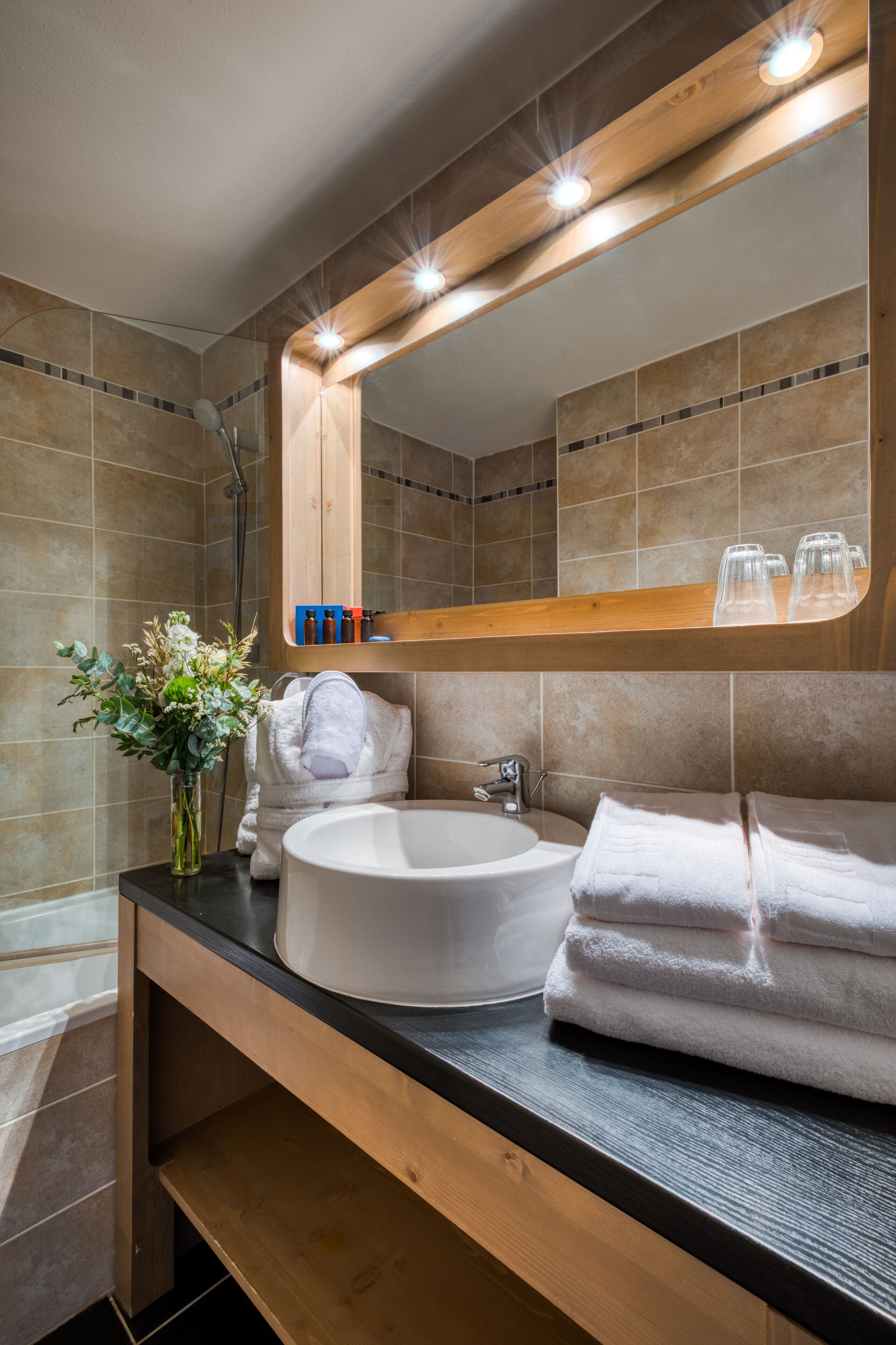 Une salle de bain moderne avec un lavabo rond, un grand miroir et un meuble-lavabo en bois.