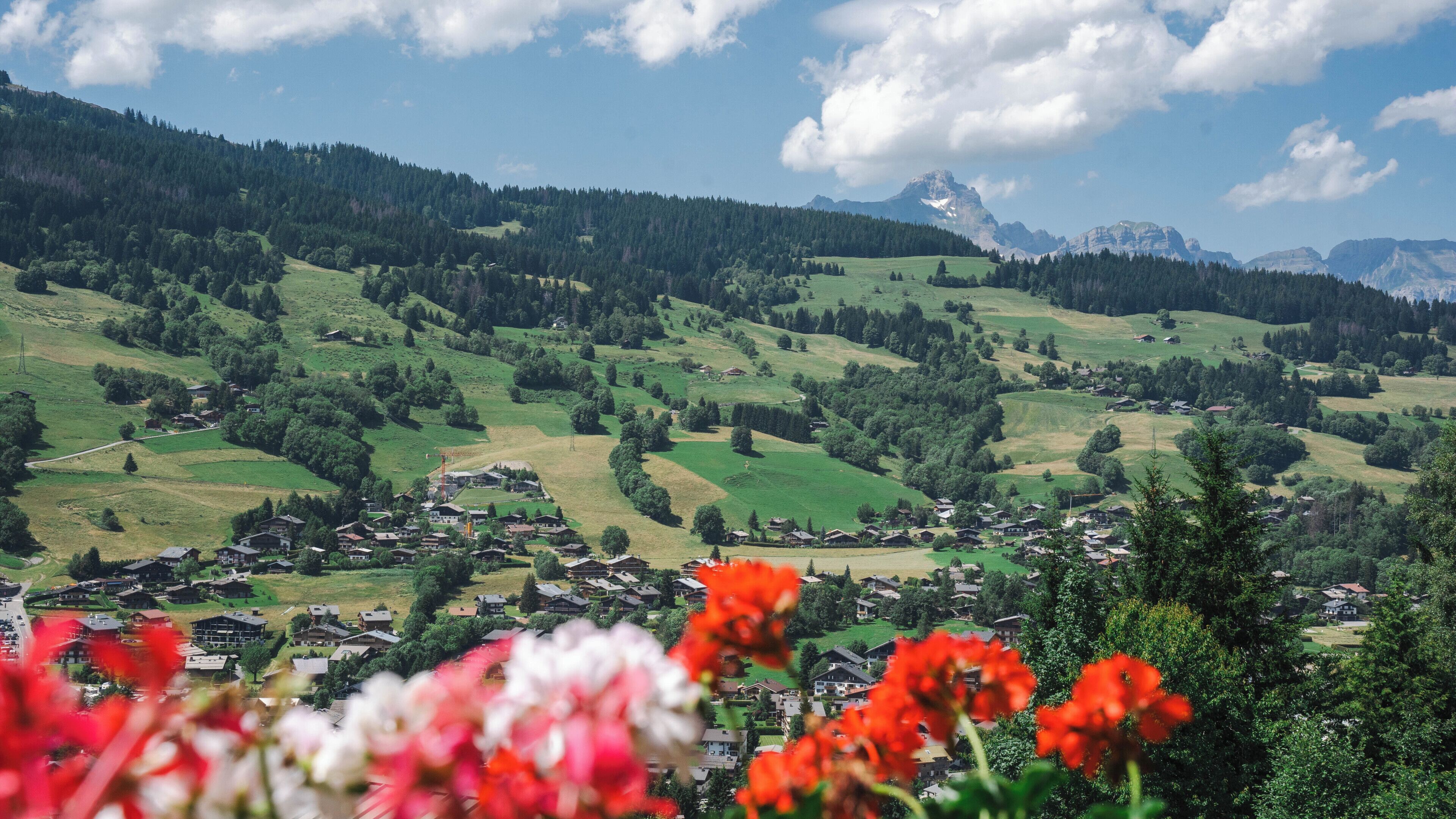 Un paisaje montañoso con un pueblo en el valle, rodeado de vegetación y árboles.