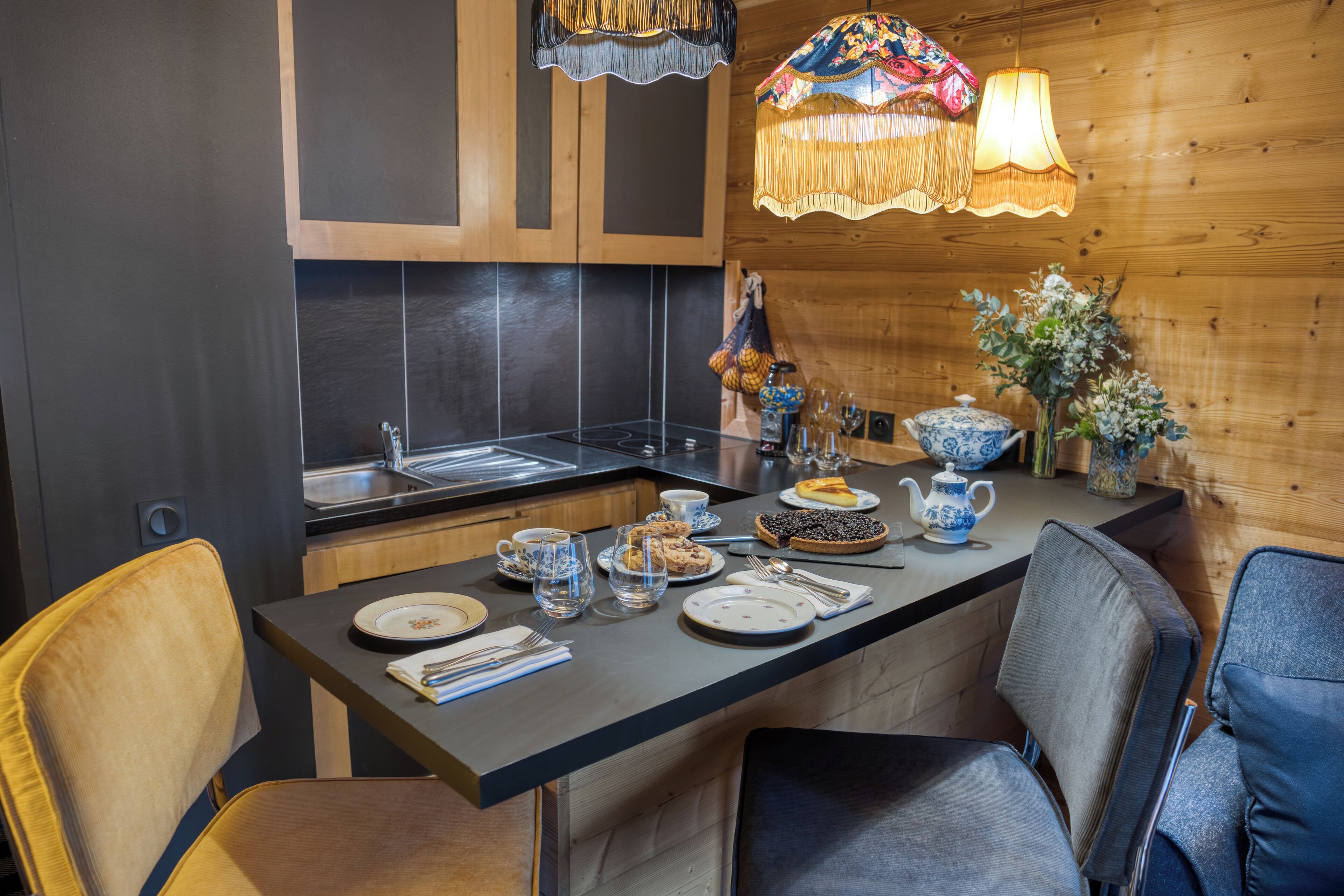 Una cocina moderna con armarios oscuros, una isla central con asientos y un candelabro decorativo.