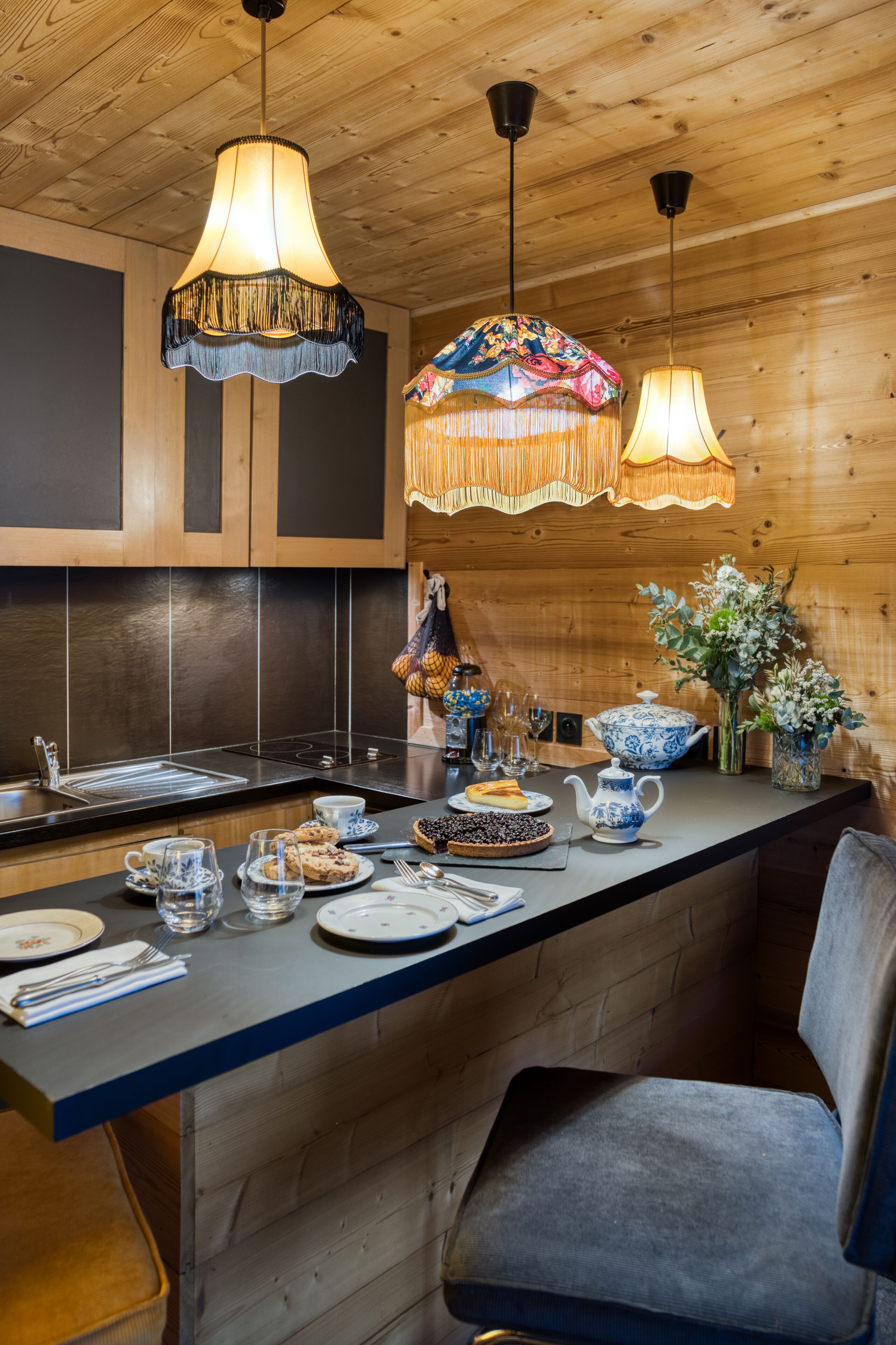 Una cocina moderna con paneles de madera, una zona de bar y lámparas colgantes.