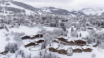 Eine schneebedeckte Lodge mit mehreren Gebäuden, umgeben von Bäumen und Bergen.