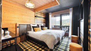 Habitación con paneles de madera, una cama, una mesa y vistas al exterior.