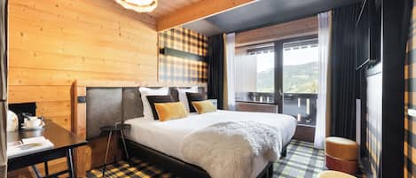 A wooden-paneled room with a bed, a table, and a view of the outdoors.