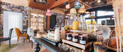 A cozy room with wooden beams, a dining table with breakfast items, and a bookshelf.
