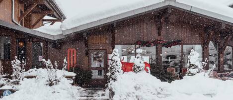 A wooden building with a snow-covered roof and a red door.