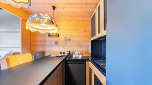 Una cocina compacta con paredes de madera, lavavajillas negro y encimera negra.