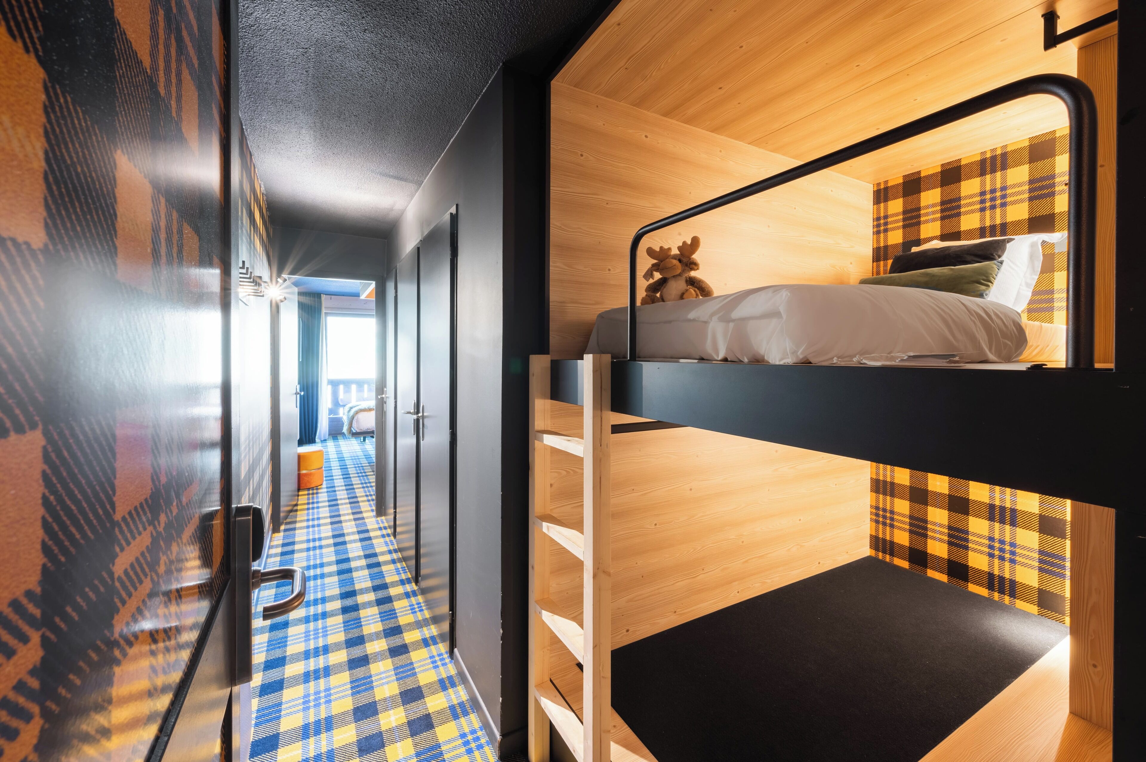 A bunk bed with a plaid headboard, a checkered floor, and a door with a glass panel.