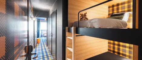 A bunk bed with a plaid headboard, a checkered floor, and a door with a glass panel.