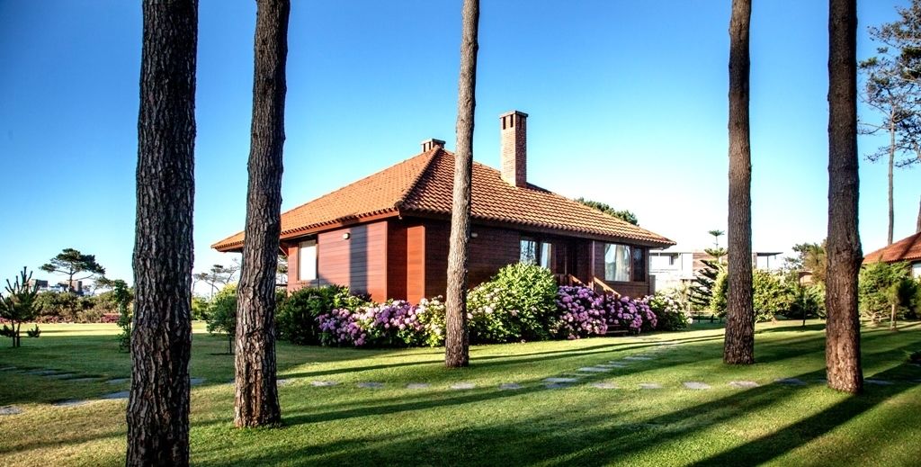 A house with a red-tiled roof, surrounded by a well-maintained lawn and tall trees.