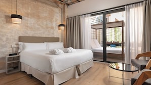Una habitación de hotel moderna con una cama grande, una mesa de vidrio y vistas al área exterior.