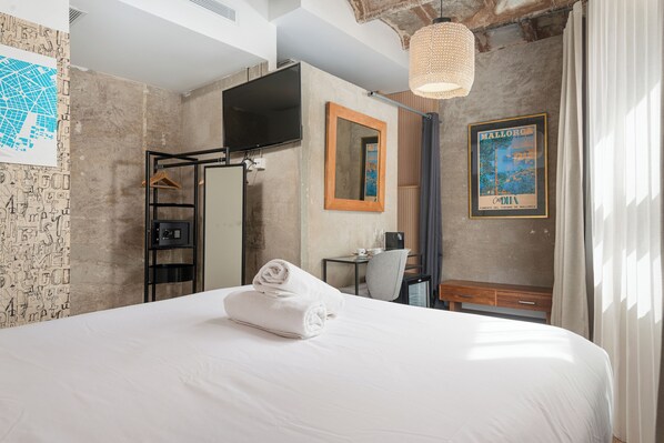 A hotel room with a large bed, a television, a mirror, a map on the wall, and a window with curtains. - Brondo Architect Hotel (Palma de Mallorca)