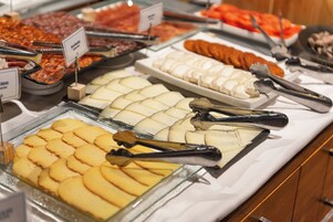 Ein Buffet mit verschiedenen Speisen, darunter Aufschnitt, Käse und Gebäck, angeordnet auf Glasplatten.