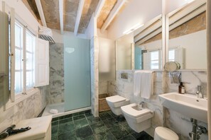A bathroom with a shower, two toilets, a sink, and a mirror. - Brondo Architect Hotel (Palma de Mallorca)