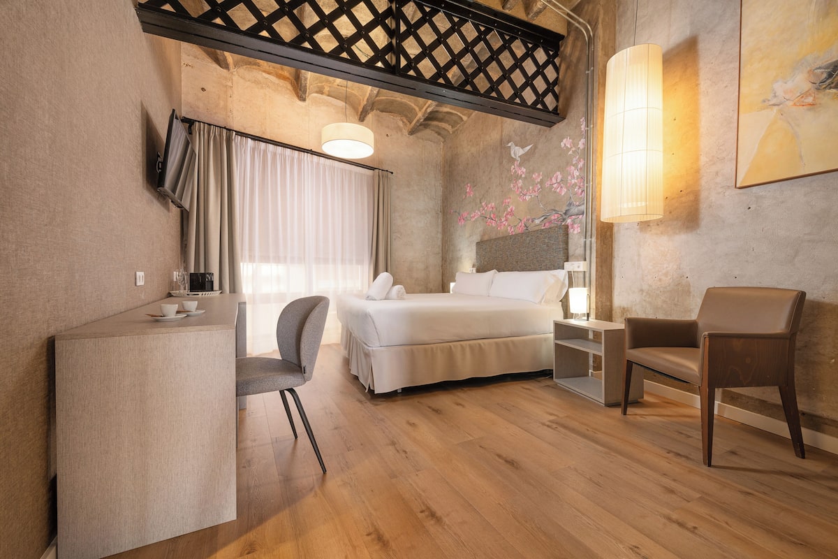 Una habitación de hotel con una cama, un escritorio, una silla y un sofá.