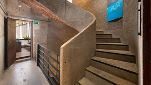 Una escalera en espiral con un muro de hormigón y un cartel azul.