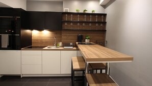 Una cocina moderna con una isla de madera, armarios blancos y un refrigerador negro.