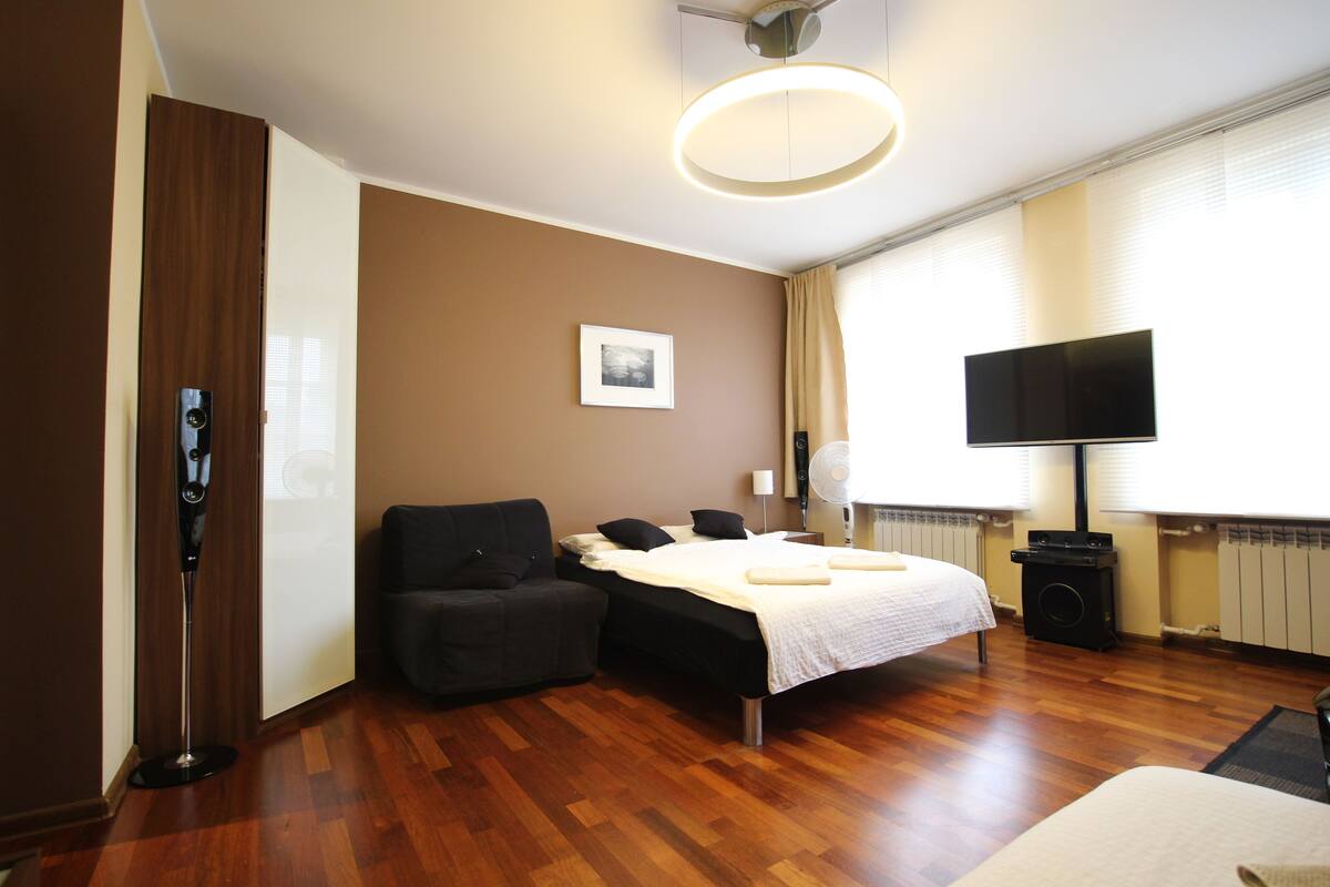 Una habitación de hotel con una cama, un sofá, un televisor y un radiador.