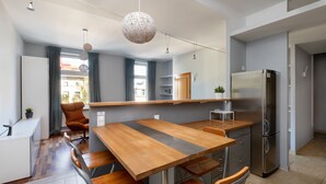 Una cocina moderna con una mesa de comedor de madera, electrodomésticos de acero inoxidable y una lámpara colgante.