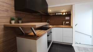 Una cocina moderna con armarios de madera, horno empotrado y pileta de acero inoxidable.