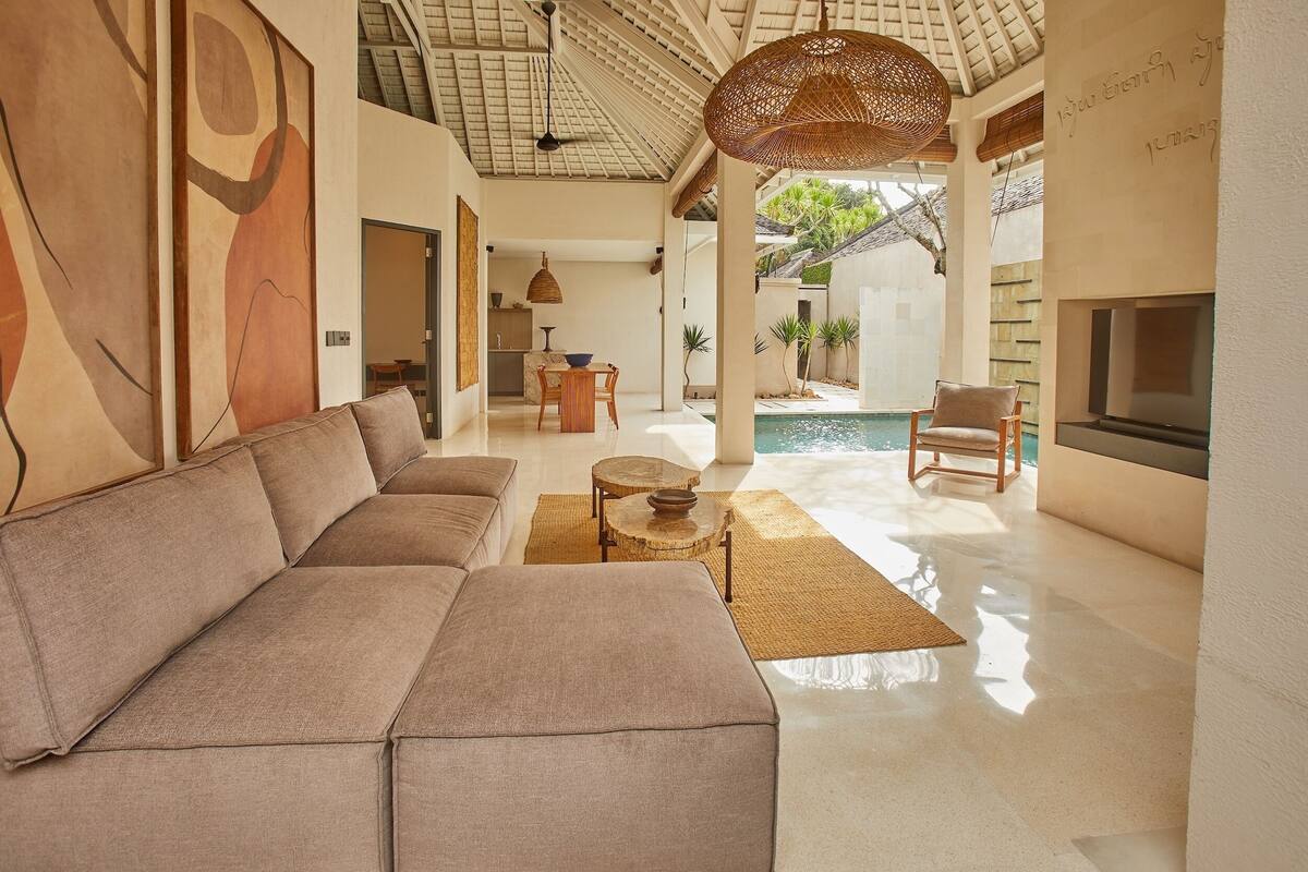 Amplia sala de estar con sofá, mesa de comedor y vista a la piscina.
