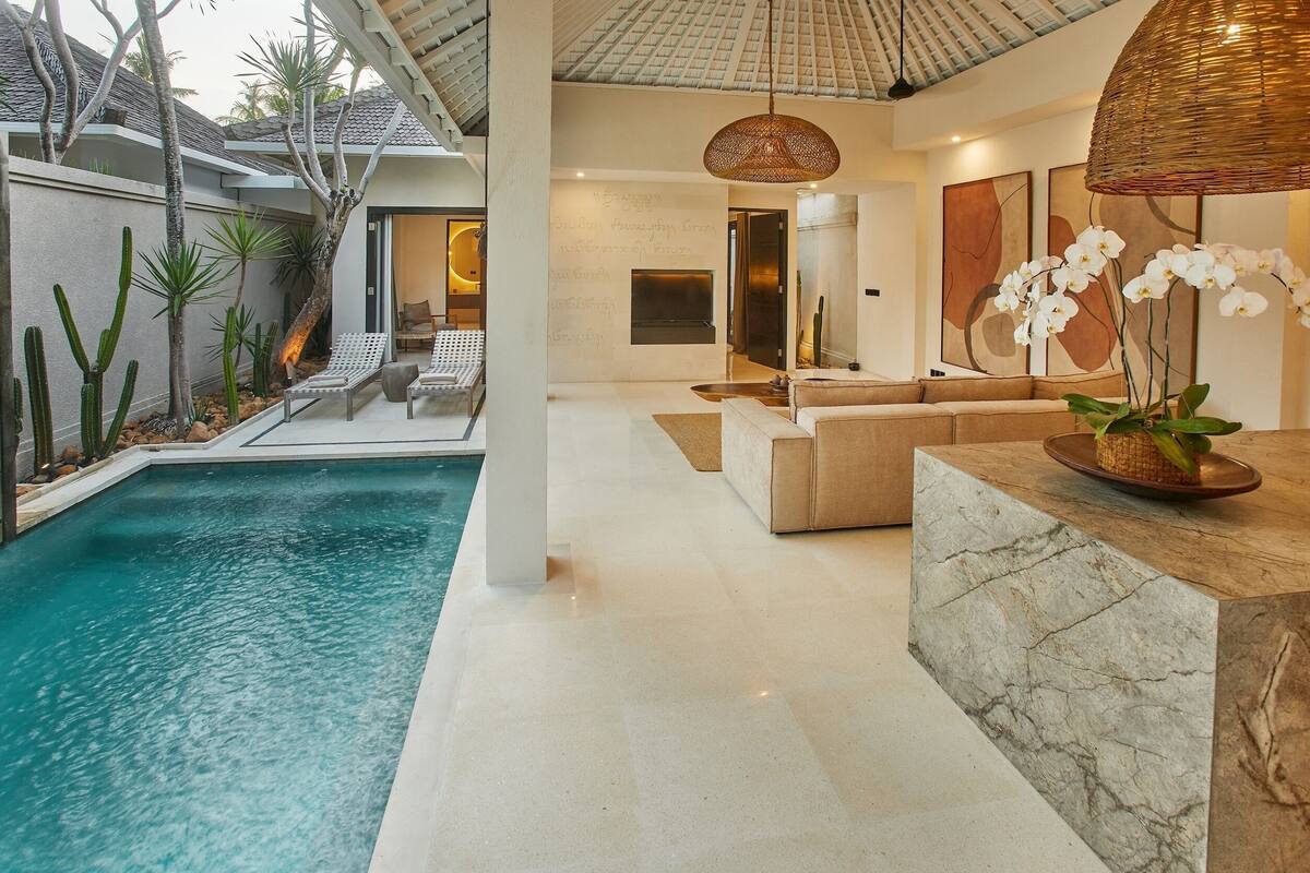 Un área de piscina interior moderna con un salón, asientos y una planta de orquídea decorativa.