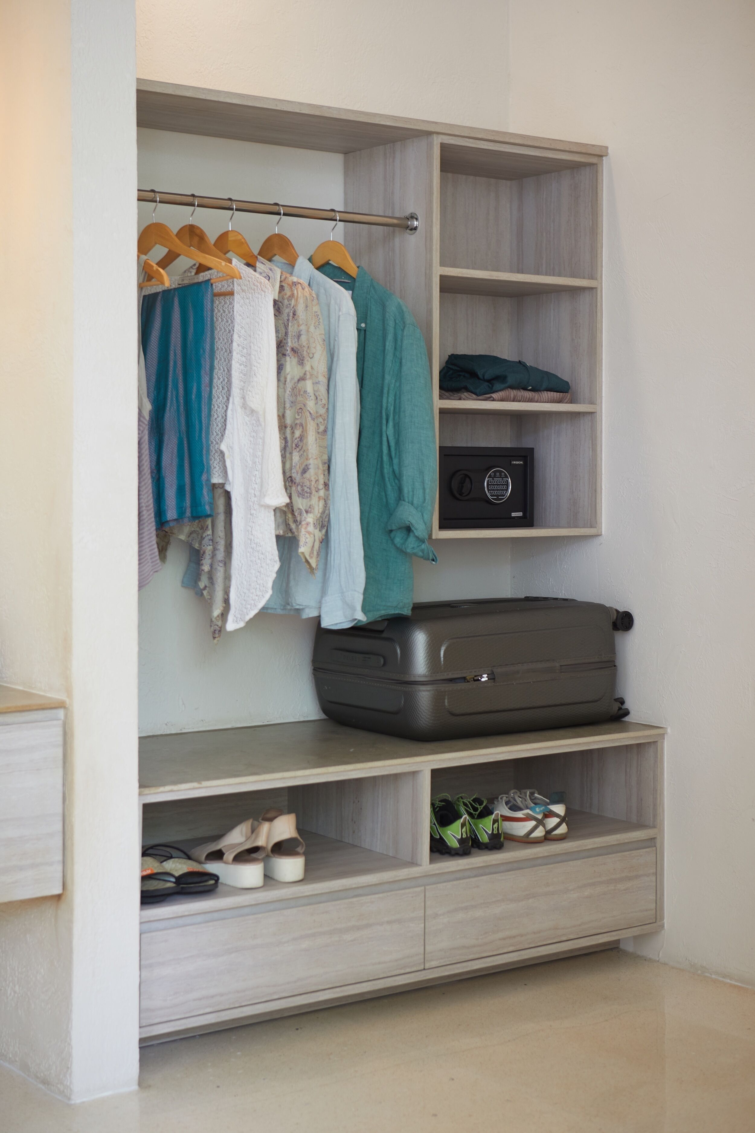 Um closet amplo com roupas penduradas, prateleiras e uma mala.