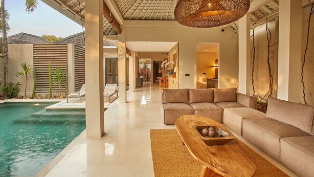 Un espacio moderno con piscina, una mesa de centro de madera y un sofá color beige.
