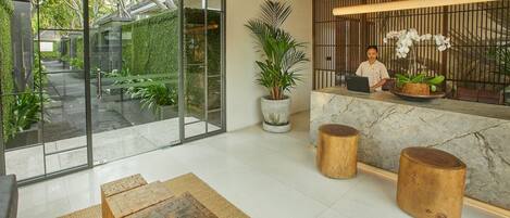 A modern reception area with a receptionist, a large glass window, and a reception desk.