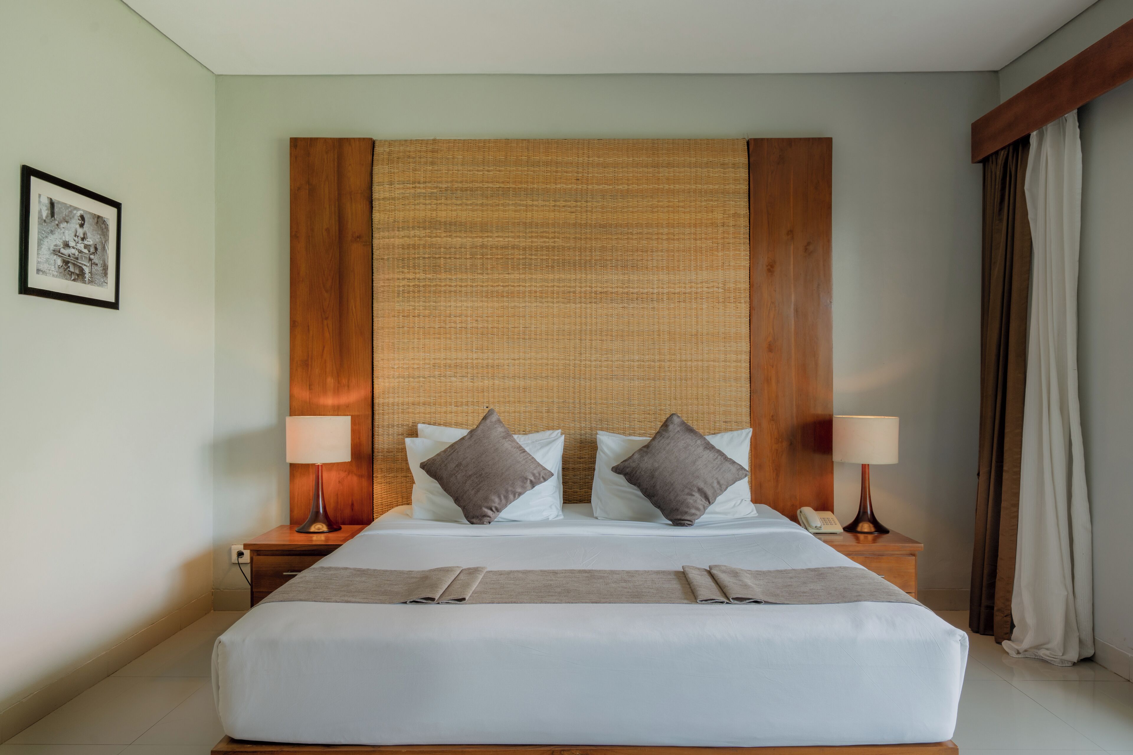 Habitación de hotel con una cama grande, dos mesitas de noche, un cabecero de madera y un cuadro en la pared.