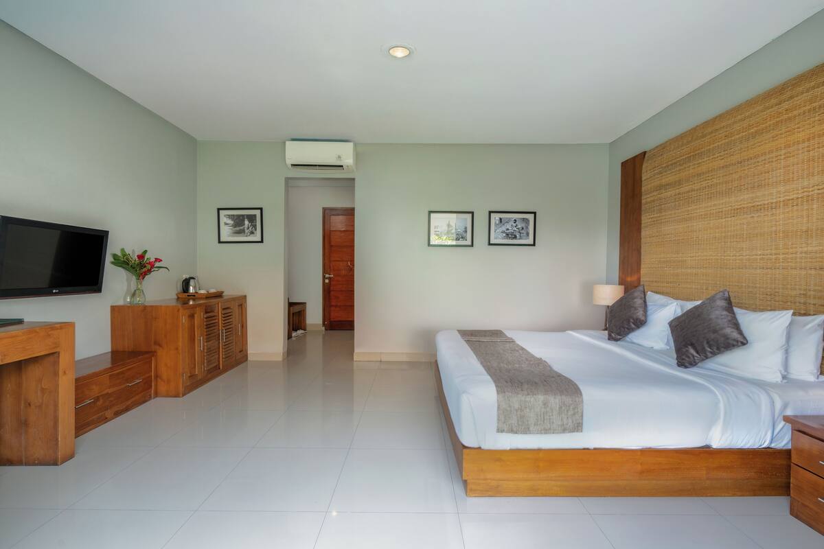 A modern bedroom with a large bed, wooden furniture, a flat-screen TV, and framed pictures on the wall.