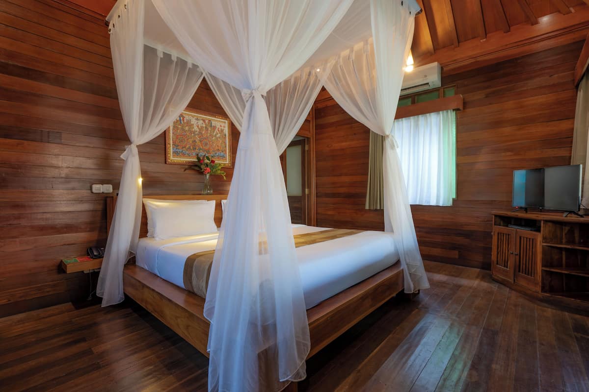 A wooden cabin-style room with a four-poster bed, a television, and a wooden cabinet.