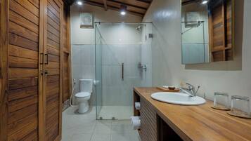 A modern bathroom with a wooden vanity, a glass shower enclosure, and a large mirror.