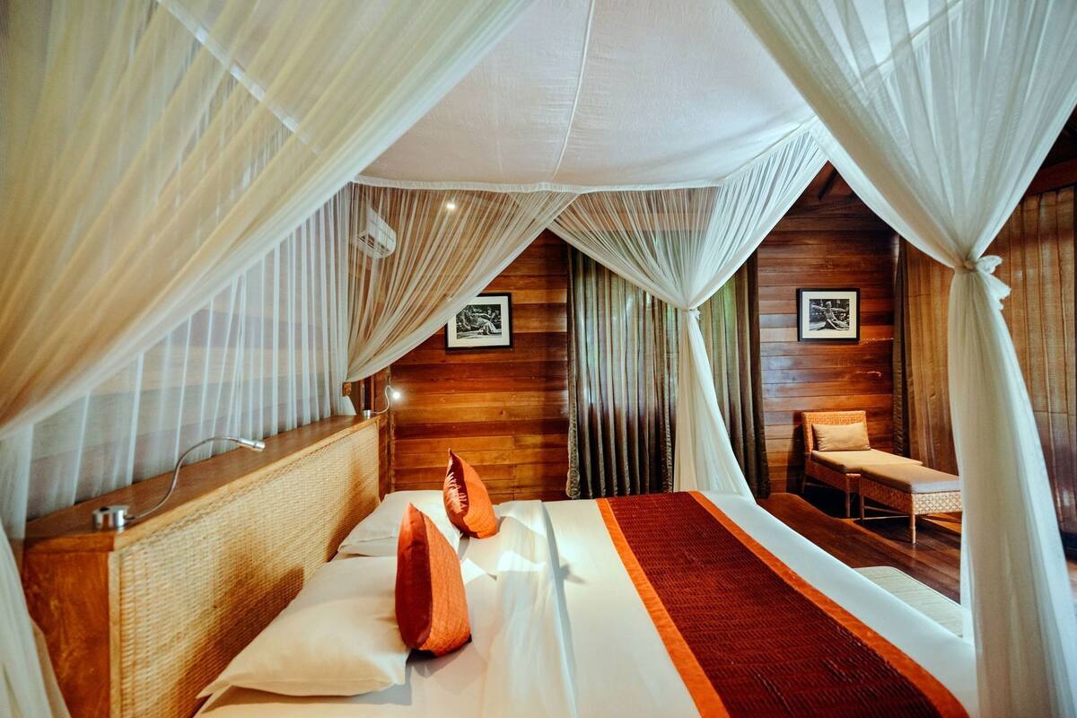 A room with a bed, a bedside table, a chair, and a wooden wall.