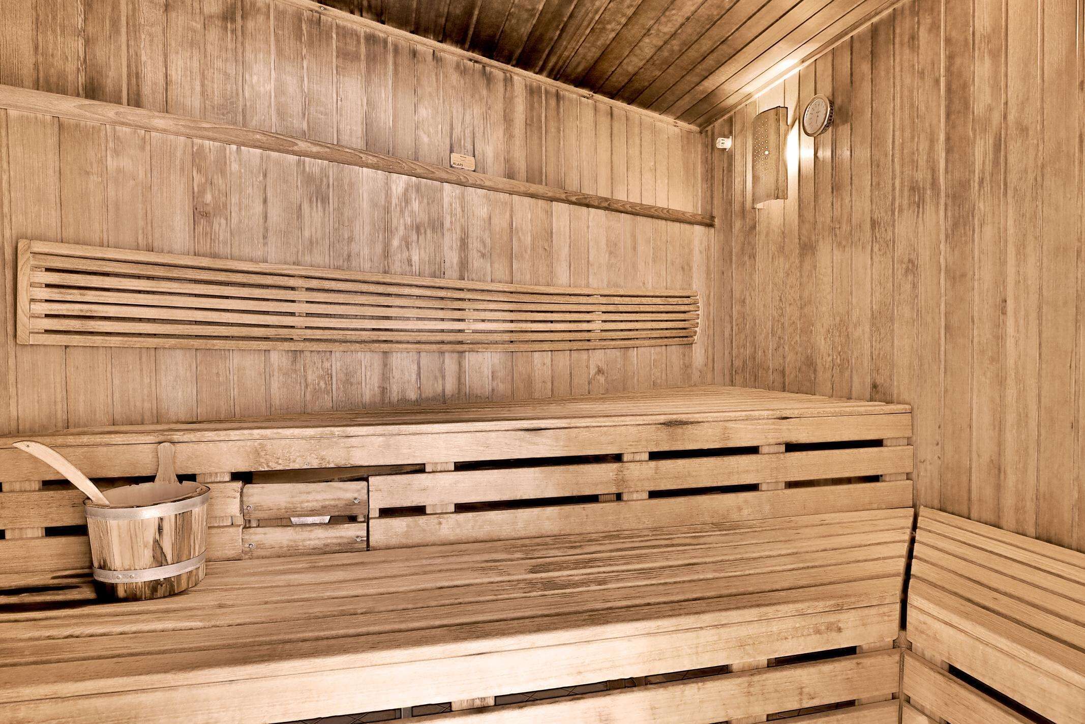 A wooden sauna with benches and a bucket.
